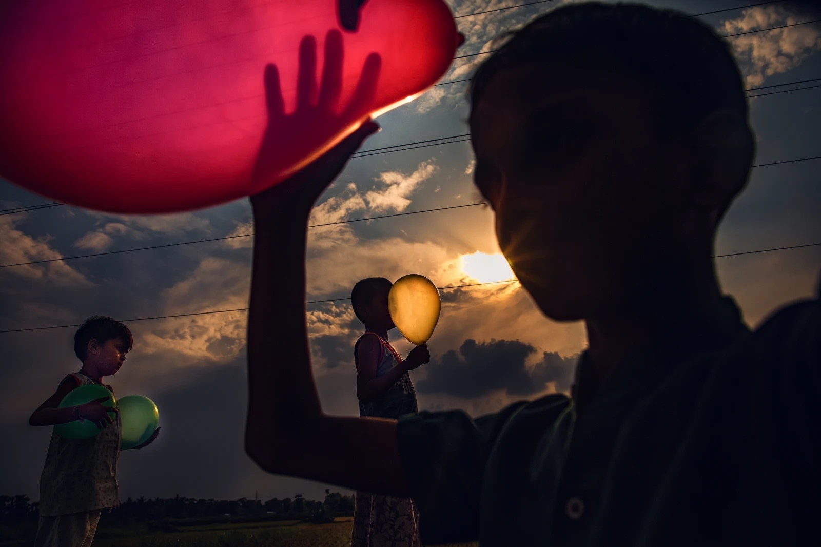 Children with colourful balloons at sunset — photograph by Anjan Ghosh